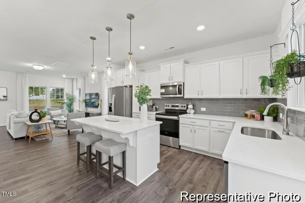 a kitchen with stainless steel appliances kitchen island granite countertop a sink a stove a refrigerator and white cabinets