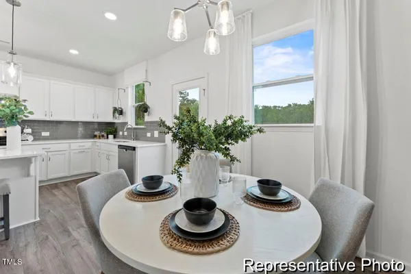 a kitchen with stainless steel appliances granite countertop a sink a stove and white cabinets with wooden floor