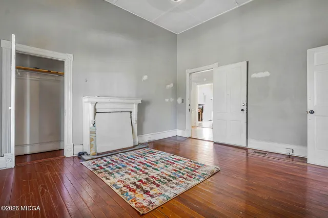 an empty room with wooden floor and a rug