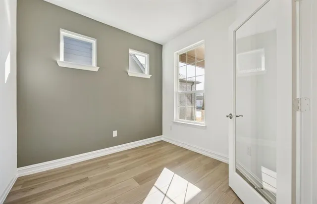 a view of an empty room with wooden floor and a window