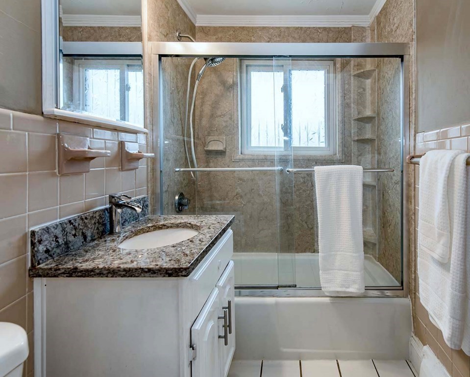 62 Bryon Road, Unit 6 Boston, MA 02467 - Photo 14 of 23 a bathroom with a granite countertop sink and a mirror
