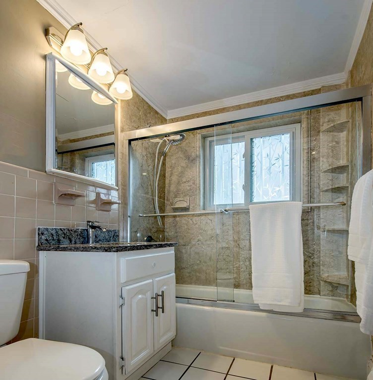 62 Bryon Road, Unit 6 Boston, MA 02467 - Photo 16 of 23 a bathroom with a granite countertop sink a toilet a mirror and shower