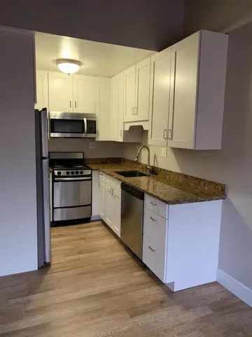 a kitchen with stainless steel appliances granite countertop a stove a sink and a microwave