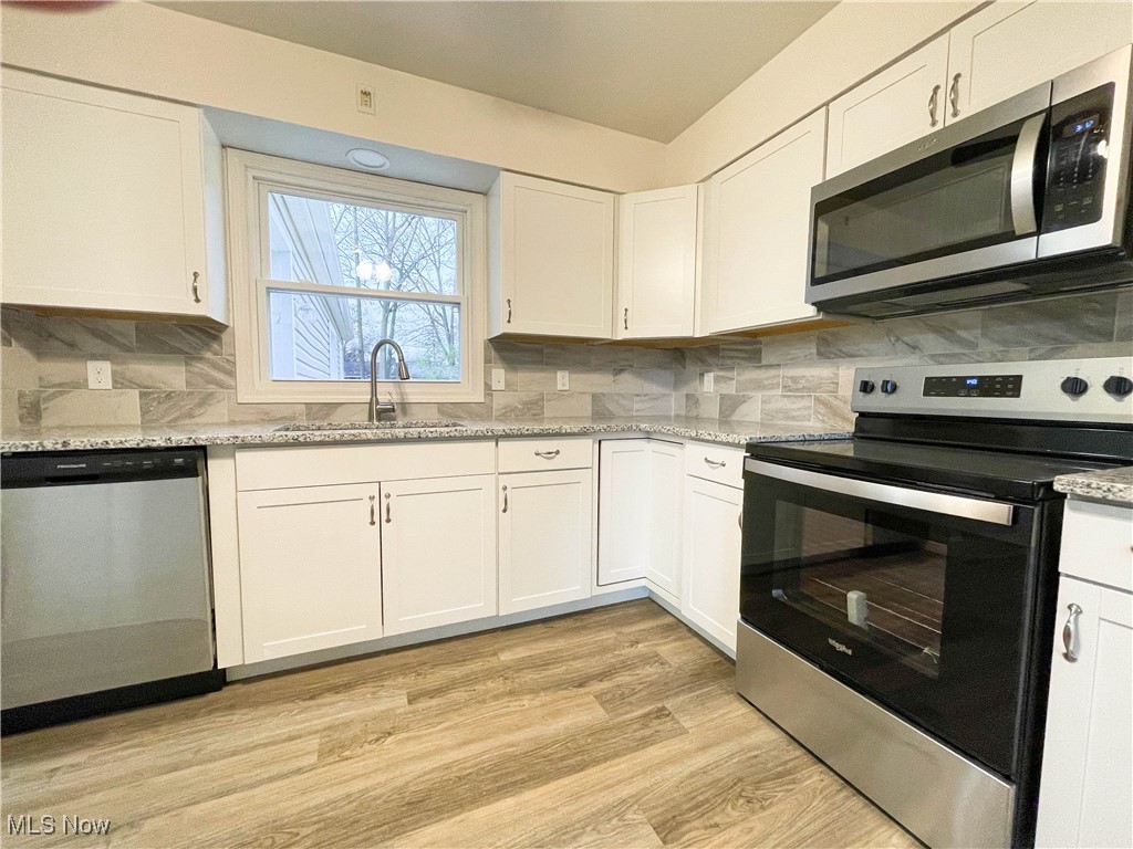 4949 East Radio Road Youngstown, OH 44515 - Photo 12 of 37 Kitchen with light hardwood / wood-style floors, white cabinetry, sink, and appliances with stainless steel finishes