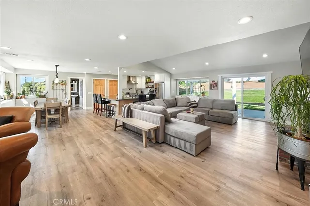 a large kitchen with stainless steel appliances a sink a stove a refrigerator cabinets and wooden floor