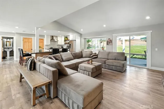 a kitchen with stainless steel appliances kitchen island granite countertop a dining table chairs and a refrigerator