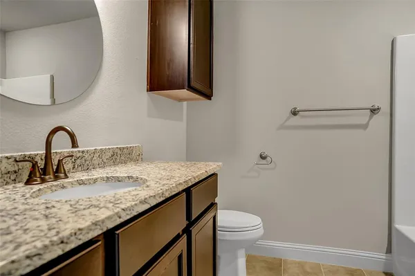 a bathroom with a granite countertop sink and a toilet