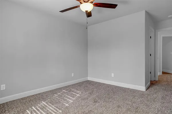 a view of an empty room and chandelier fan