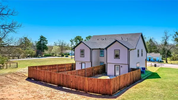 a view of a house with wooden fence and a big yard