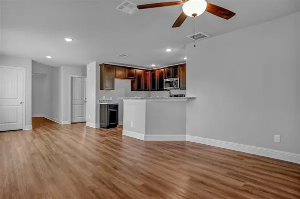 an empty room with wooden floor a ceiling fan a fireplace and windows