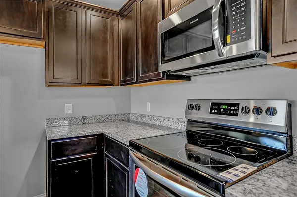 a kitchen with granite countertop a stove and a microwave