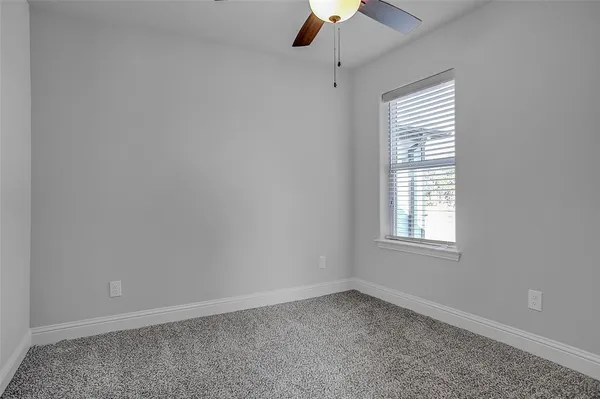 an empty room with a window and a fan
