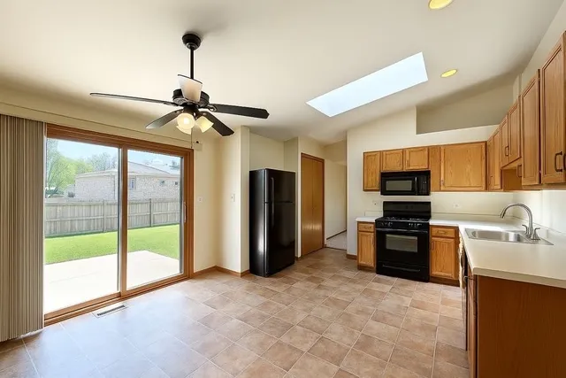 a view of a livingroom with a fireplace a ceiling fan and windows