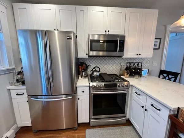 a kitchen with stainless steel appliances a refrigerator stove and white cabinets