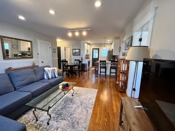 a living room with furniture kitchen view and a wooden floor