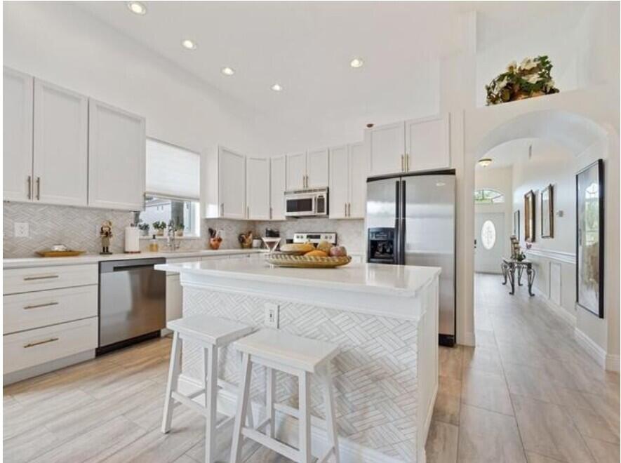 8534 Vía D Oro Boca Raton, FL 33433 - Photo 16 of 34 a kitchen with white cabinets and stainless steel appliances