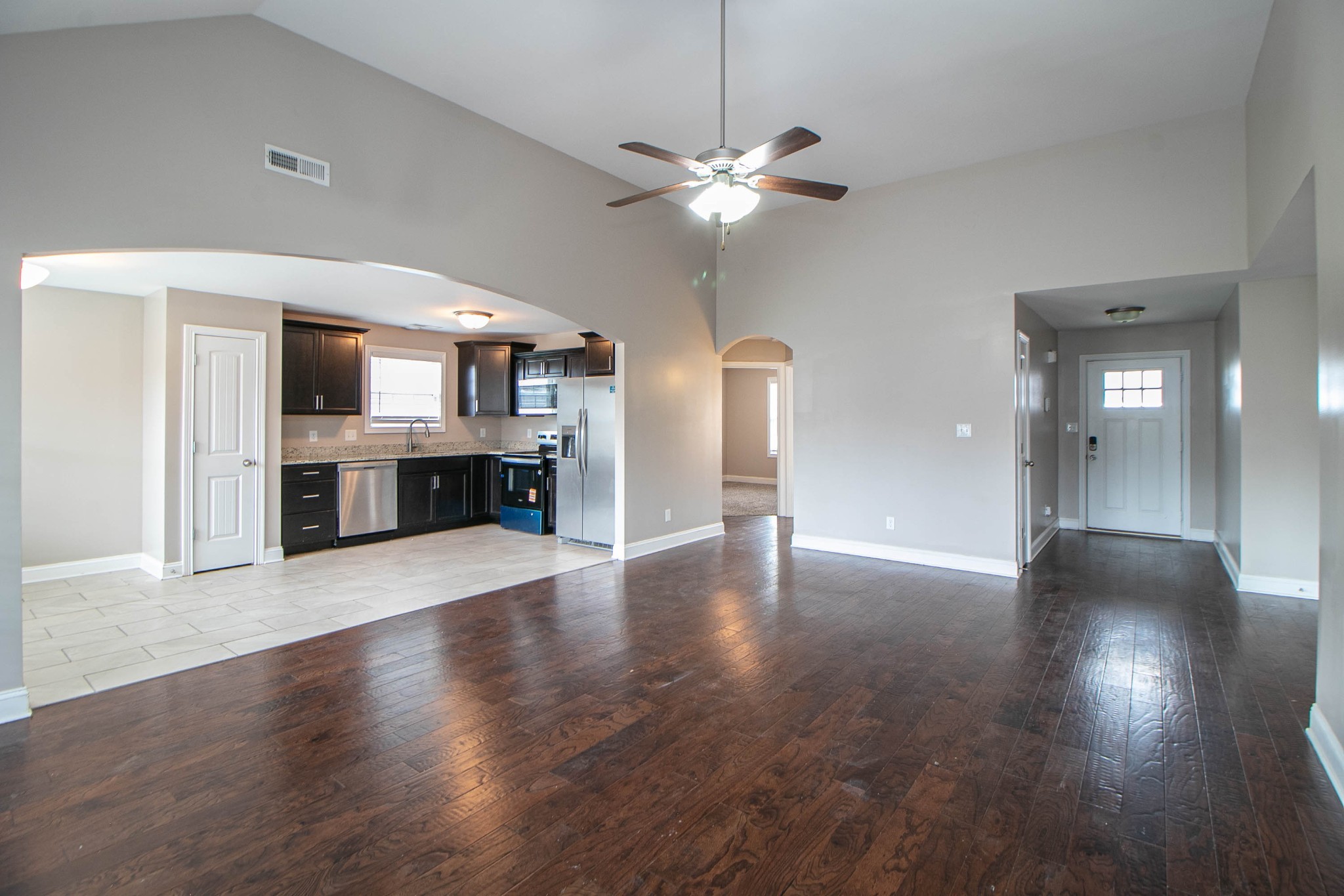 151 Ambridge Street Oak Grove, KY 42262 - Photo 7 of 30 a view of a livingroom with a kitchen a ceiling fan wooden floor and windows