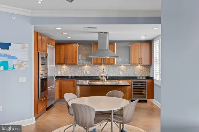 a kitchen with stainless steel appliances granite countertop a stove top oven a sink a dining table and chairs