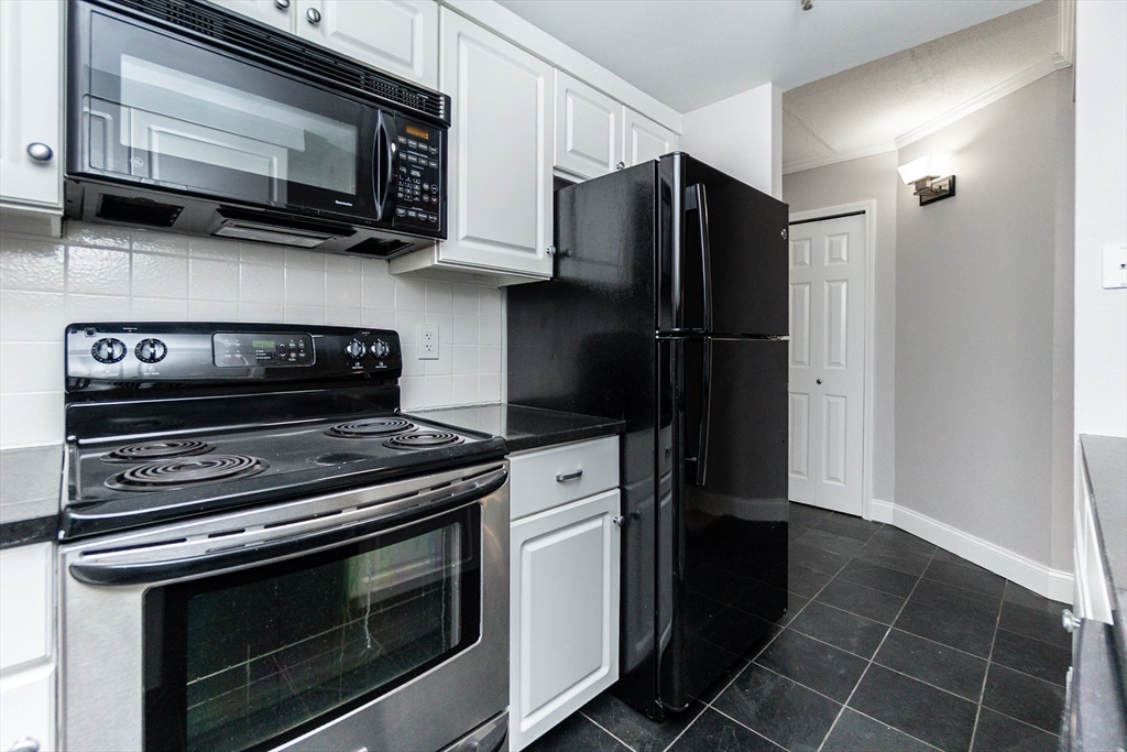 1933 Commonwealth Avenue, Unit 108 Boston, MA 02135 - Photo 5 of 27 a kitchen with stainless steel appliances a stove a microwave and cabinets