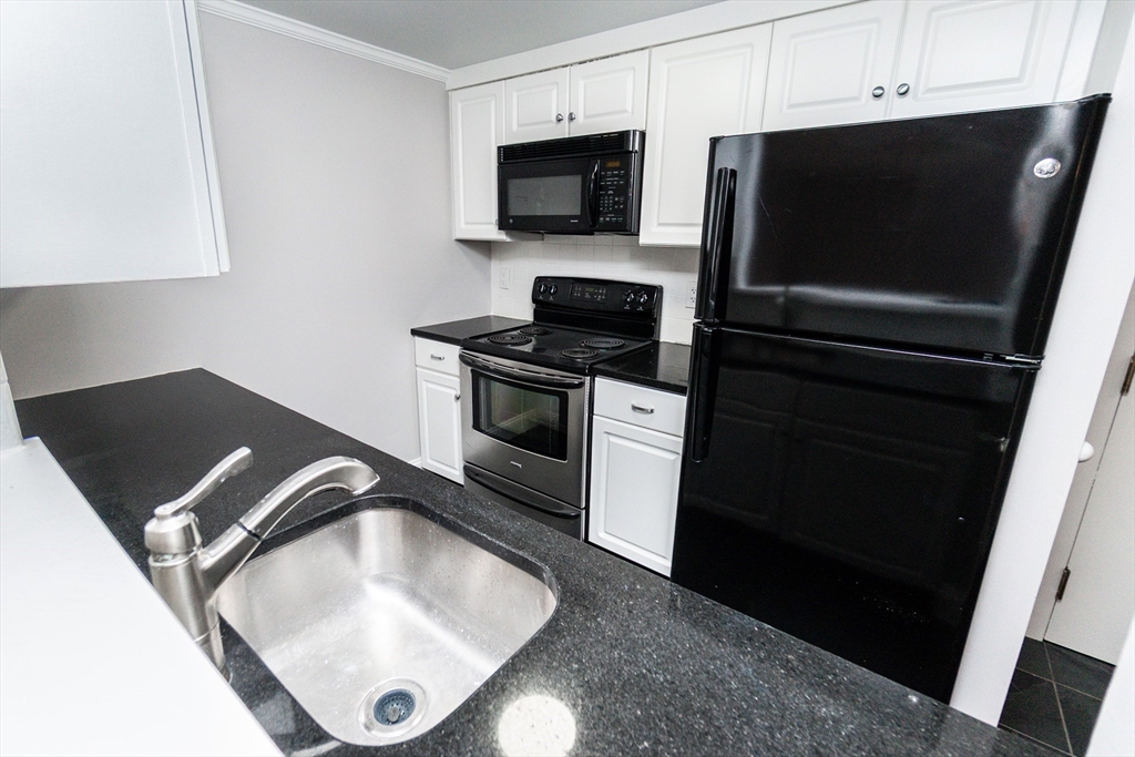 1933 Commonwealth Avenue, Unit 108 Boston, MA 02135 - Photo 7 of 27 a kitchen with a stove and a microwave