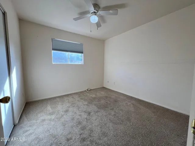 en empty room with ceiling fan and window