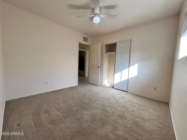 an empty room with windows and fan