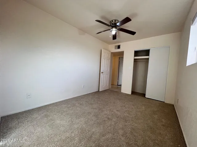 an empty room with closet and a chandelier fan