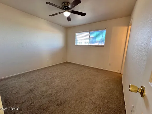 an empty room with a window and a fan