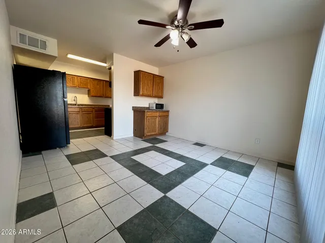 a view of a refrigerator in kitchen and an empty room
