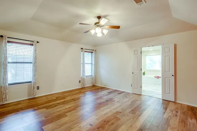a view of empty room with wooden floor and fan