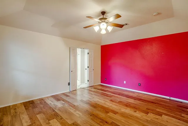 an empty room with a chandelier fan and windows