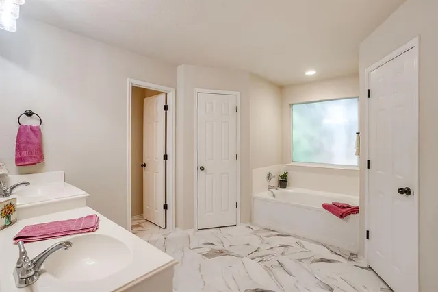 a bathroom with a tub sink and mirror