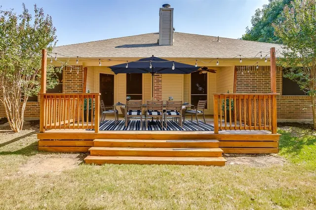 a view of a patio with table and chairs with wooden floor and fence