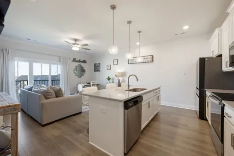 a kitchen with a sink and a stove top oven with wooden floor