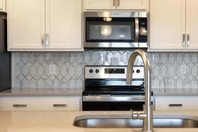 a large white kitchen with a large island oven a stove a sink a dining table and chairs with wooden floor