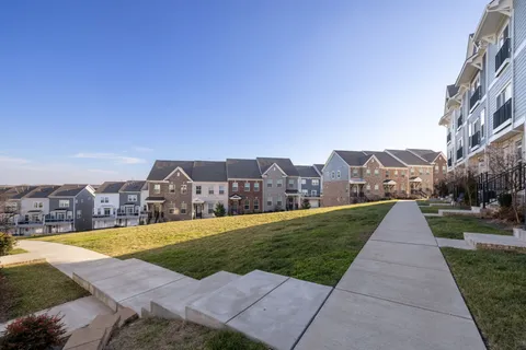 a kitchen with stainless steel appliances granite countertop a sink a stove top oven a refrigerator with white cabinets and wooden floor