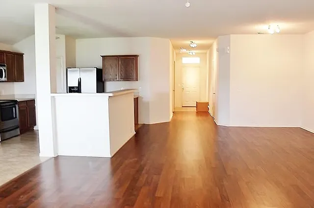 a view of a living room with kitchen and wooden floor