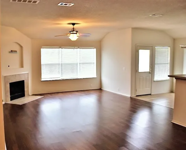 an empty room with wooden floor fireplace and windows