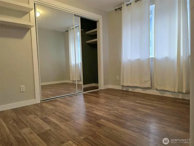 an empty room with wooden floor & closet area