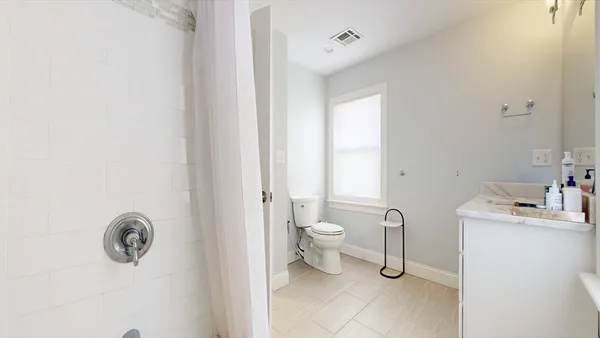 a bathroom with a toilet a sink a mirror and vanity