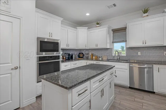 a kitchen with granite countertop white cabinets and a sink