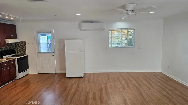 an empty room with wooden floor fireplace and windows