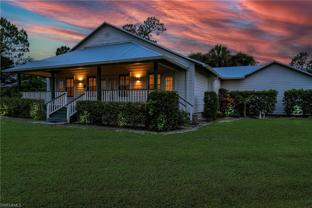 3988 Reflection Court Naples, FL 34109 - Photo 7 of 50 View of front of home featuring a lawn, a metal roof, and a porch