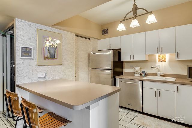 175 East Delaware Place, Unit 5609 Chicago, IL 60611 - Photo 3 of 28 a kitchen with a sink a refrigerator and cabinets