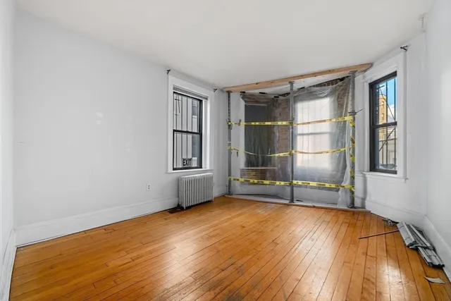 a view of an empty room with a window and wooden floor