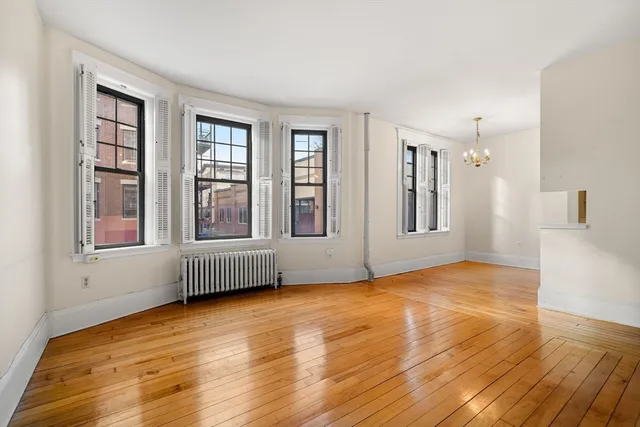 a view of an empty room with window and wooden floor