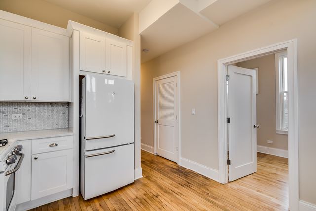a view of a kitchen with white cabinets and wooden floor