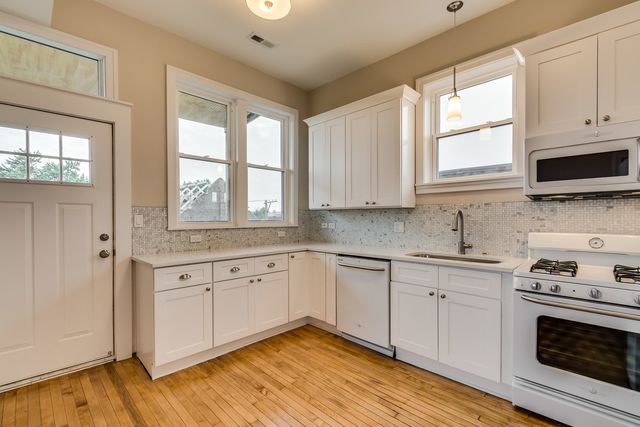 a kitchen with granite countertop white cabinets stainless steel appliances a sink and a window