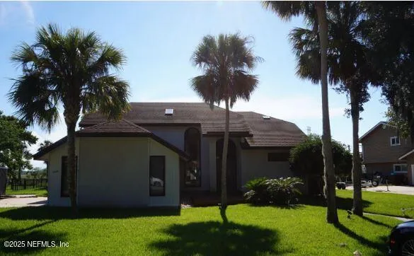 front view of house with a yard and palm trees