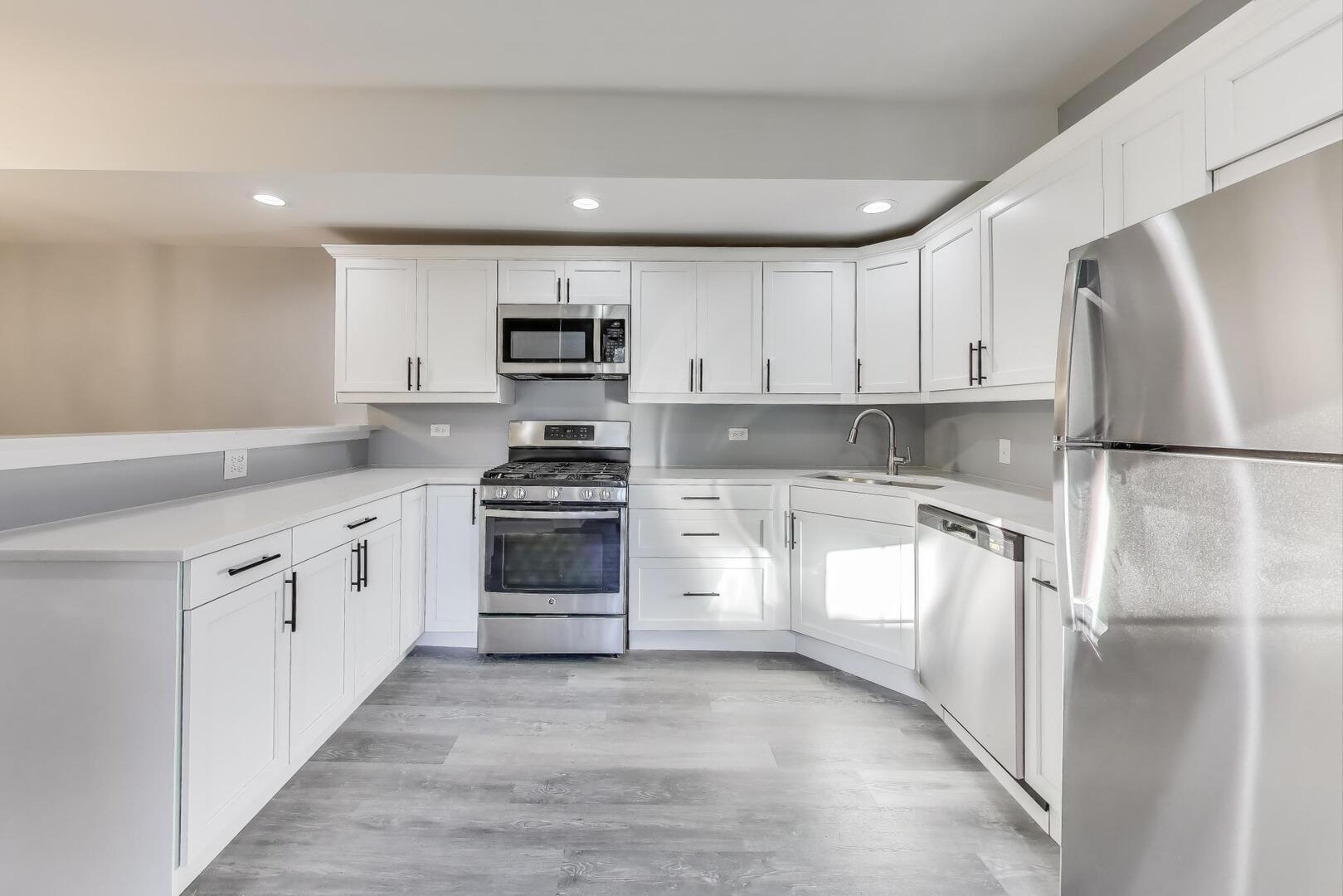 Undisclosed Address Chicago, IL 60622 - Photo 9 of 33 a kitchen with white cabinets and stainless steel appliances